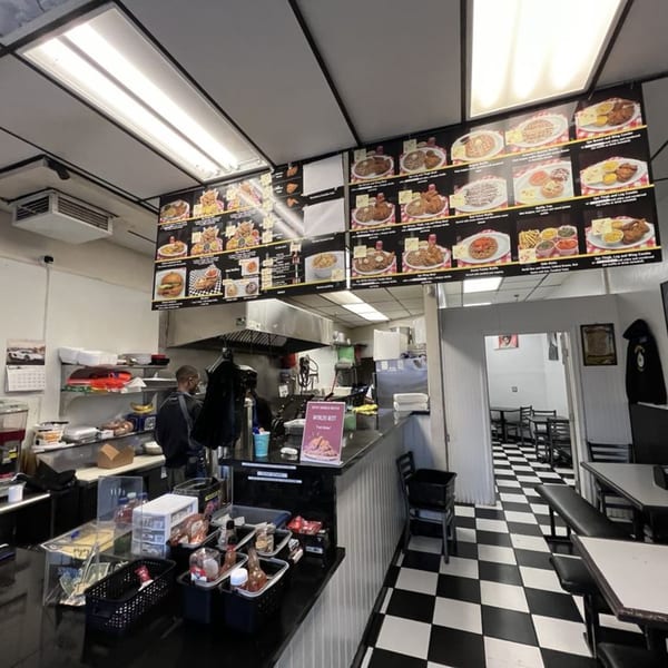 Interior of Keith’s Chicken N Waffles, showing menu boards, a counter, and a dining area with checkered floors.